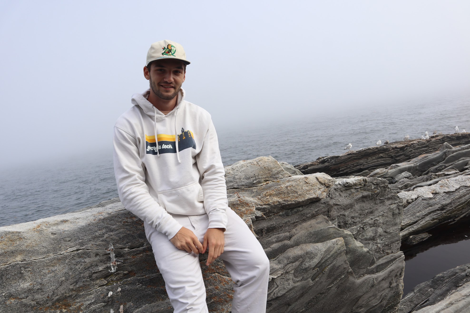 Jack sitting on rocks beside the ocean