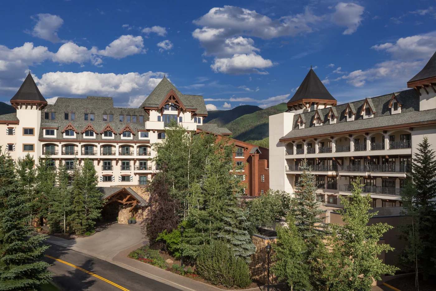The Hythe Vail on a summer day, its peaked towers framed by pine trees and green mountains