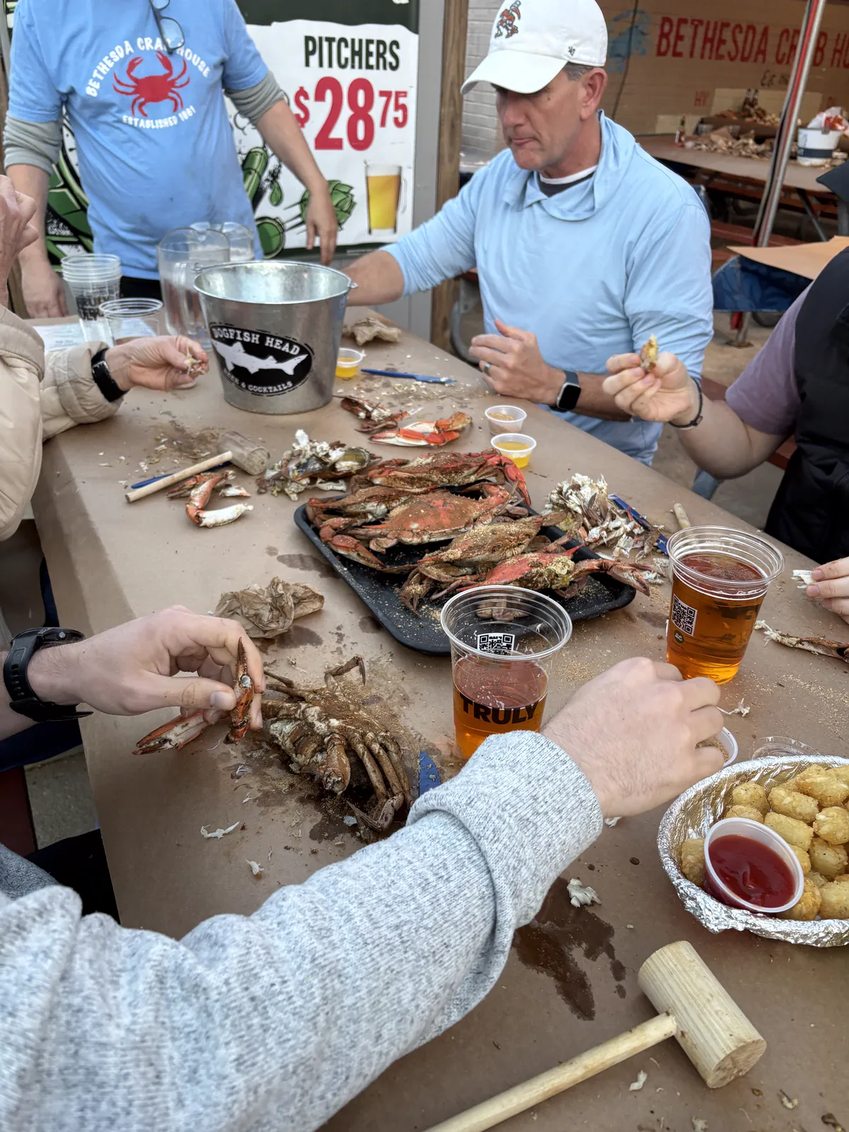 Friends and family cracking steamed crabs over pitchers of beer